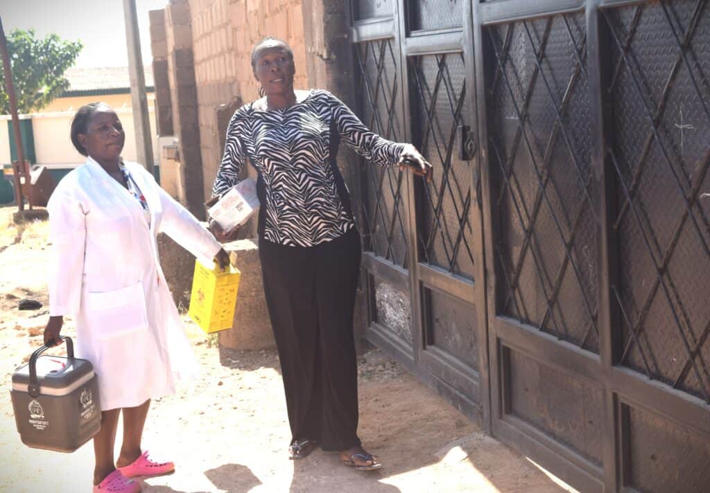 Two female health workers stand outside a Nigerian school