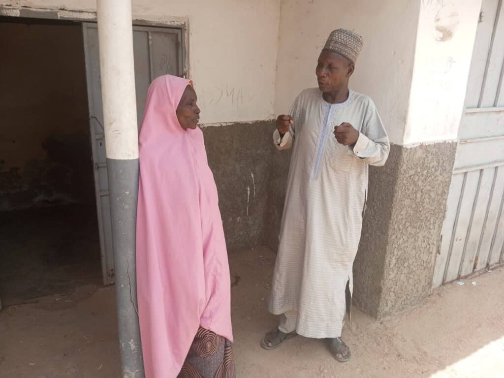 A Nigerian man speaks with a woman outside.