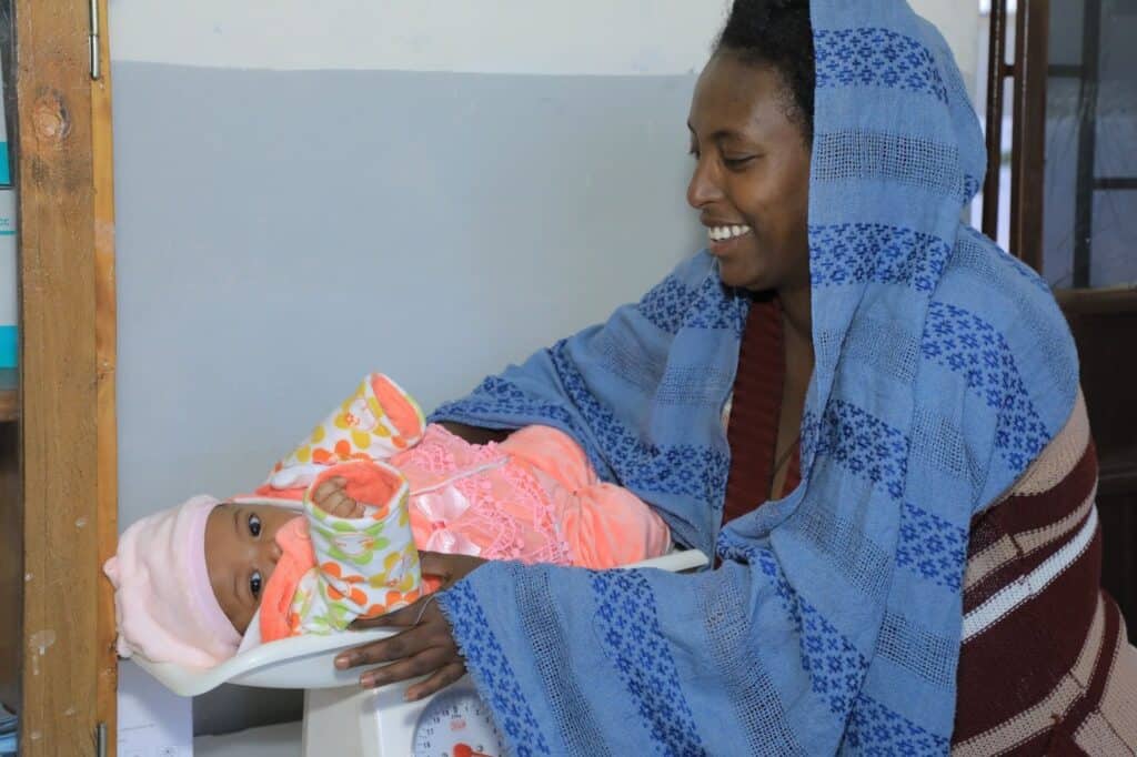 An Ethiopian mother weighs her baby.