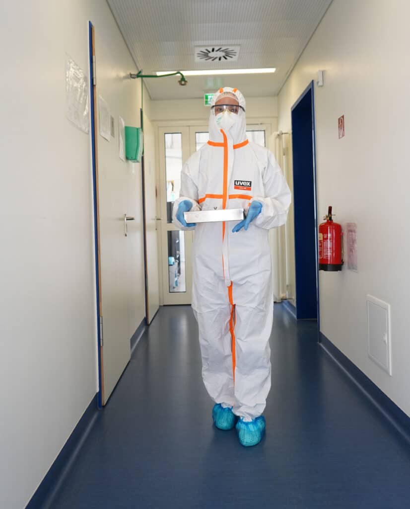 A laboratory professional in full protective gear transports COVID-19 samples for testing.