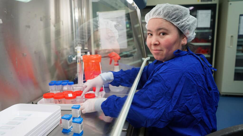 A female lab worker poses for a photo while working at her station.