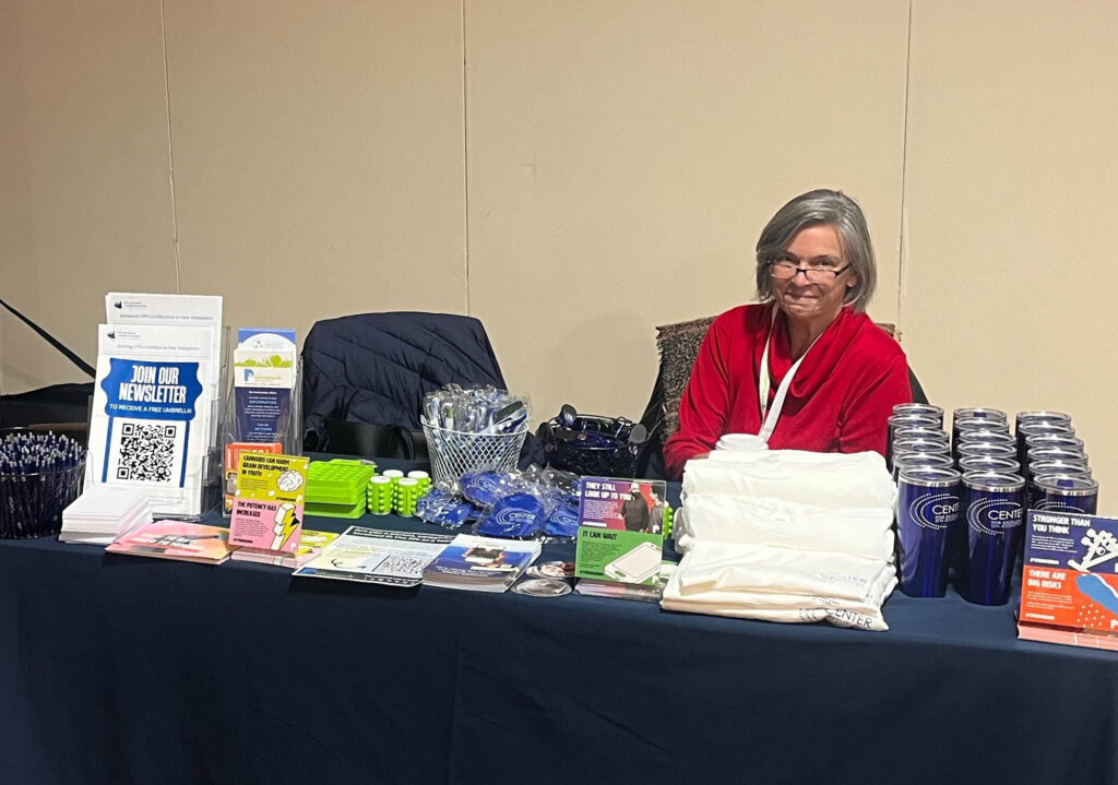 A woman sits behind a table at a conference.