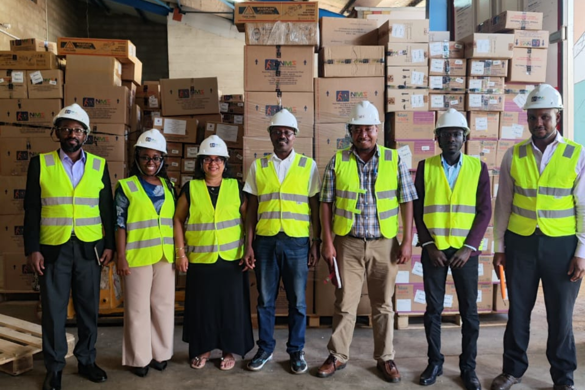 A group of people stand for a photo in a warehouse wearing safety equipment