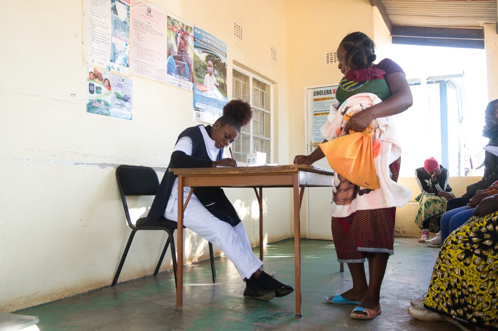 A health care worker screens clients at an integrated health clinic in Zambia.