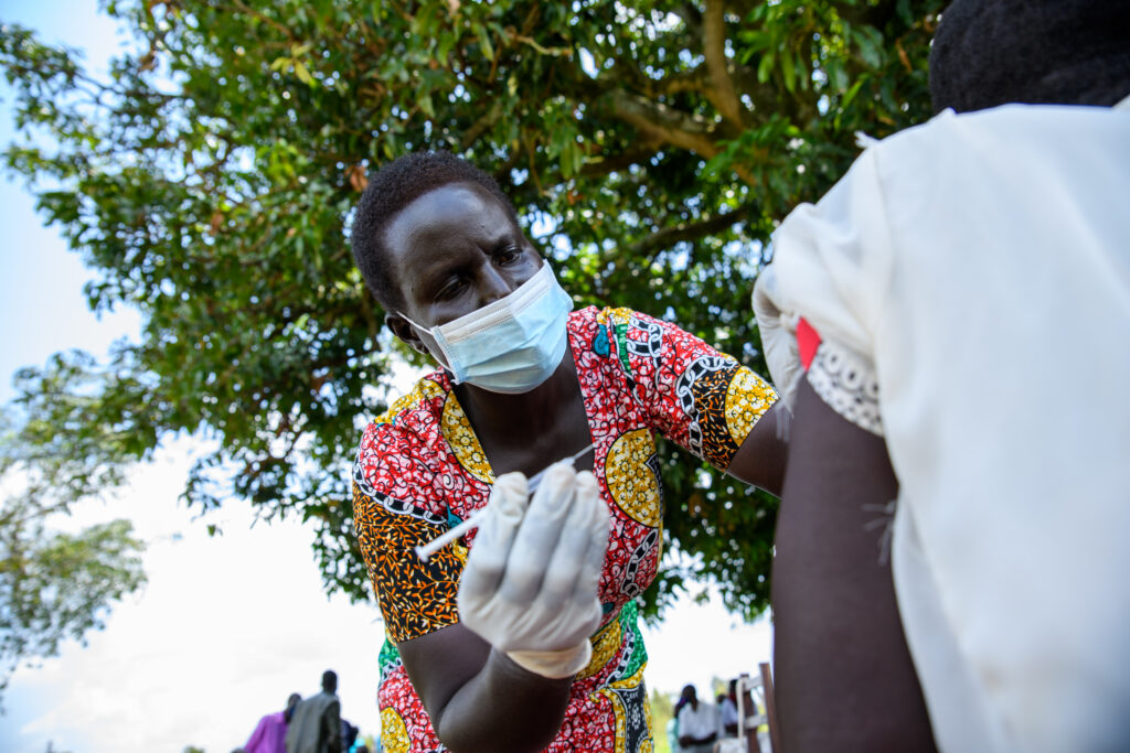 Health care worker conducts community vaccination for COVID-19 in Uganda during the height of the pandemic.