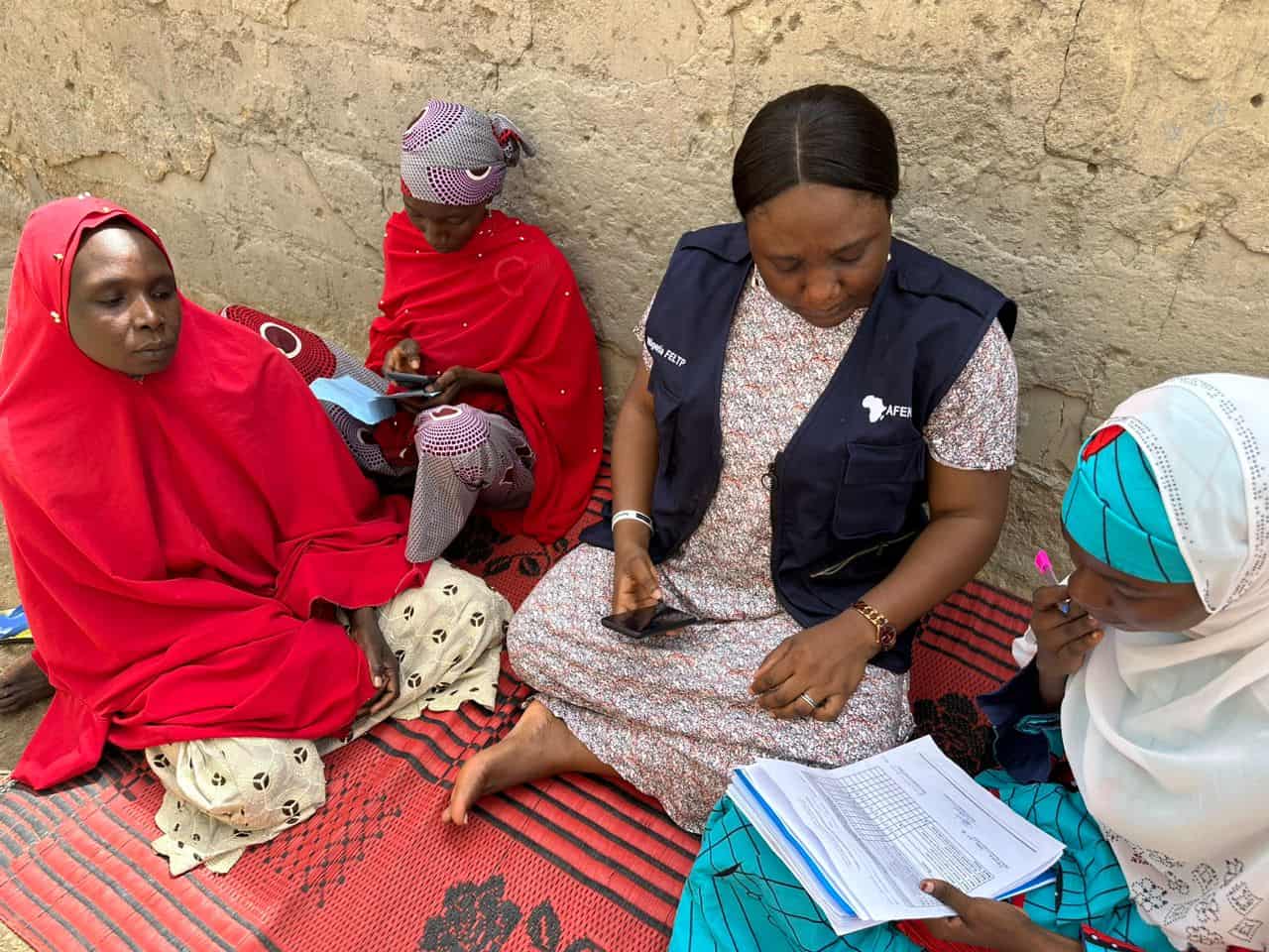 A health worker and caregivers review immunization records.