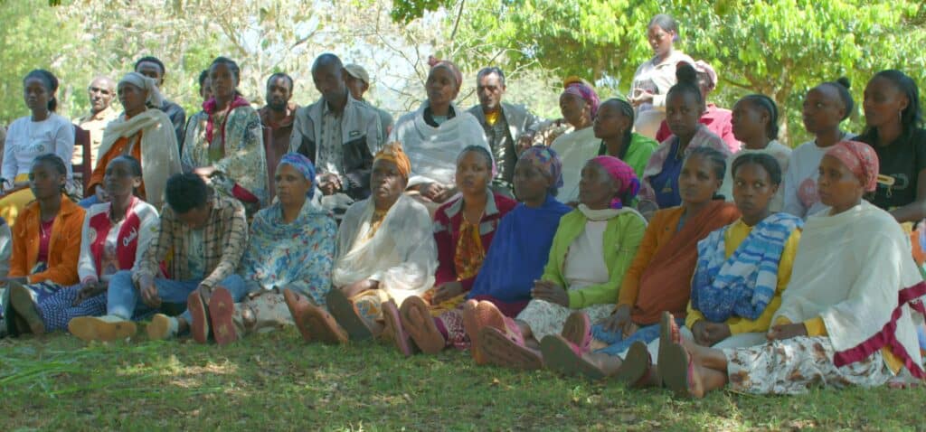 A group of Ethiopian women sit together outside during a meeting.