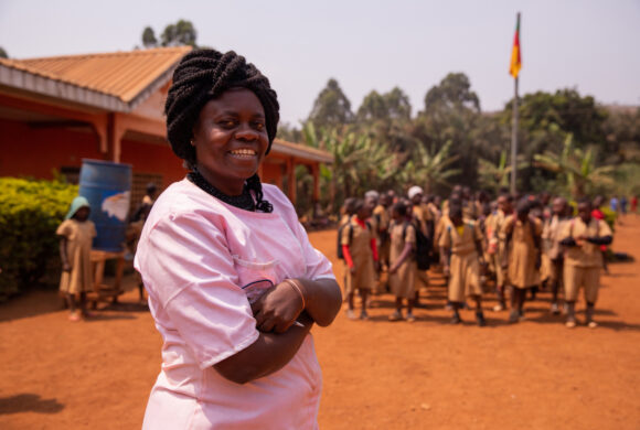 African school teacher following the pupils by singing the national anthem while raising the flag.
