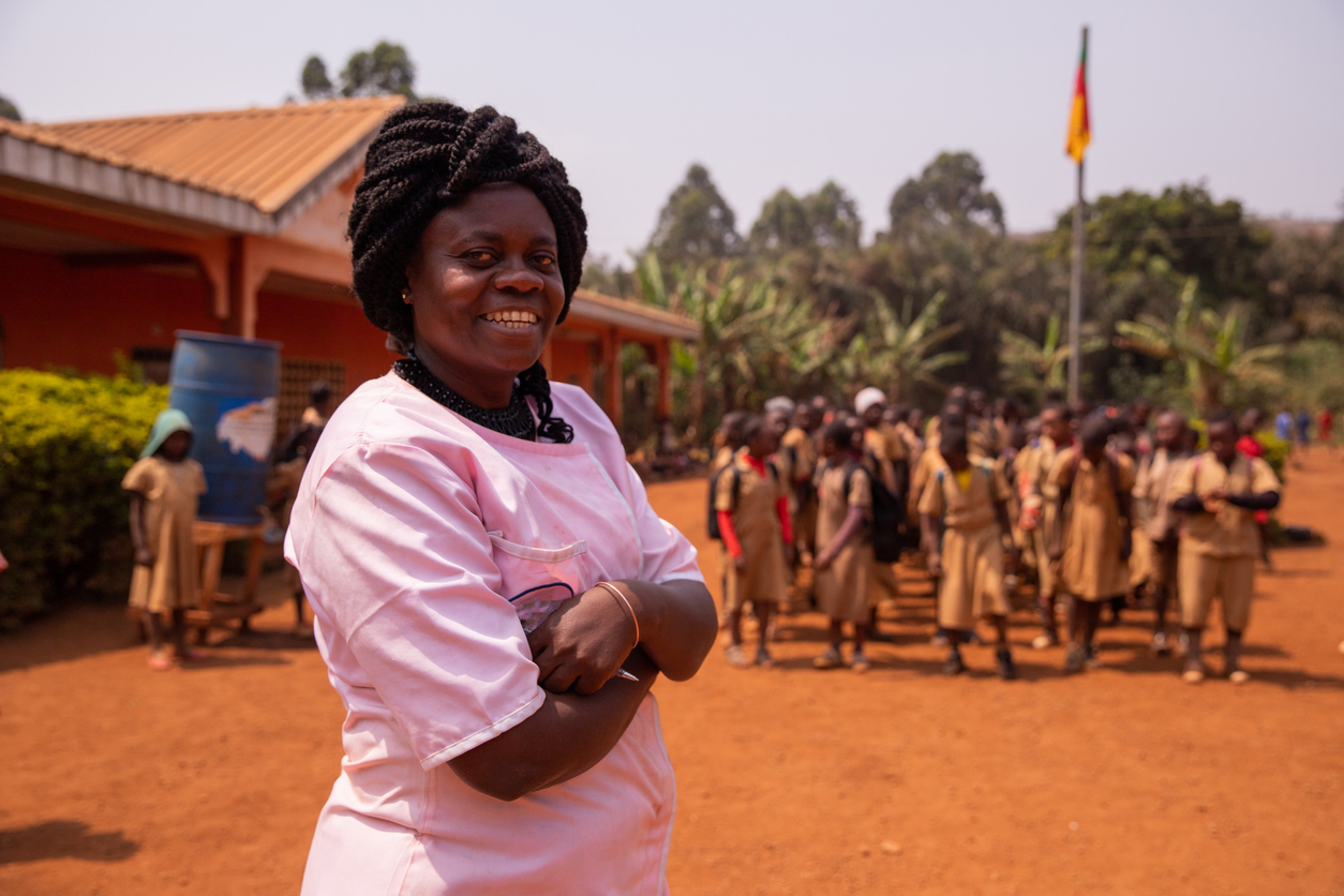 African school teacher following the pupils by singing the national anthem while raising the flag.