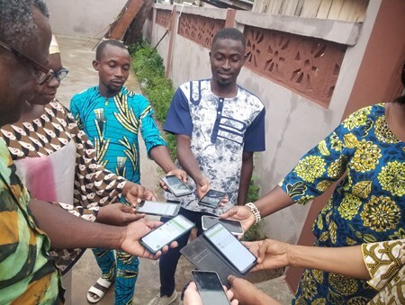 A group of people in Benin hold their mobile phones together.