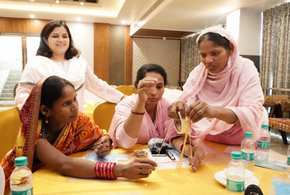 Four women who are caregivers and health workers in India participate in a workshop activity together.