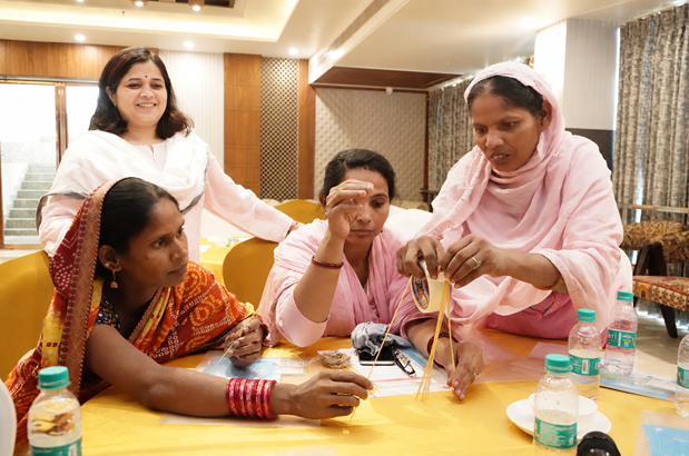 Four women who are caregivers and health workers in India participate in a workshop activity together.