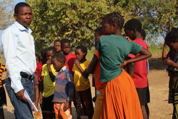 A teacher in Mozambique stands outside with his students.