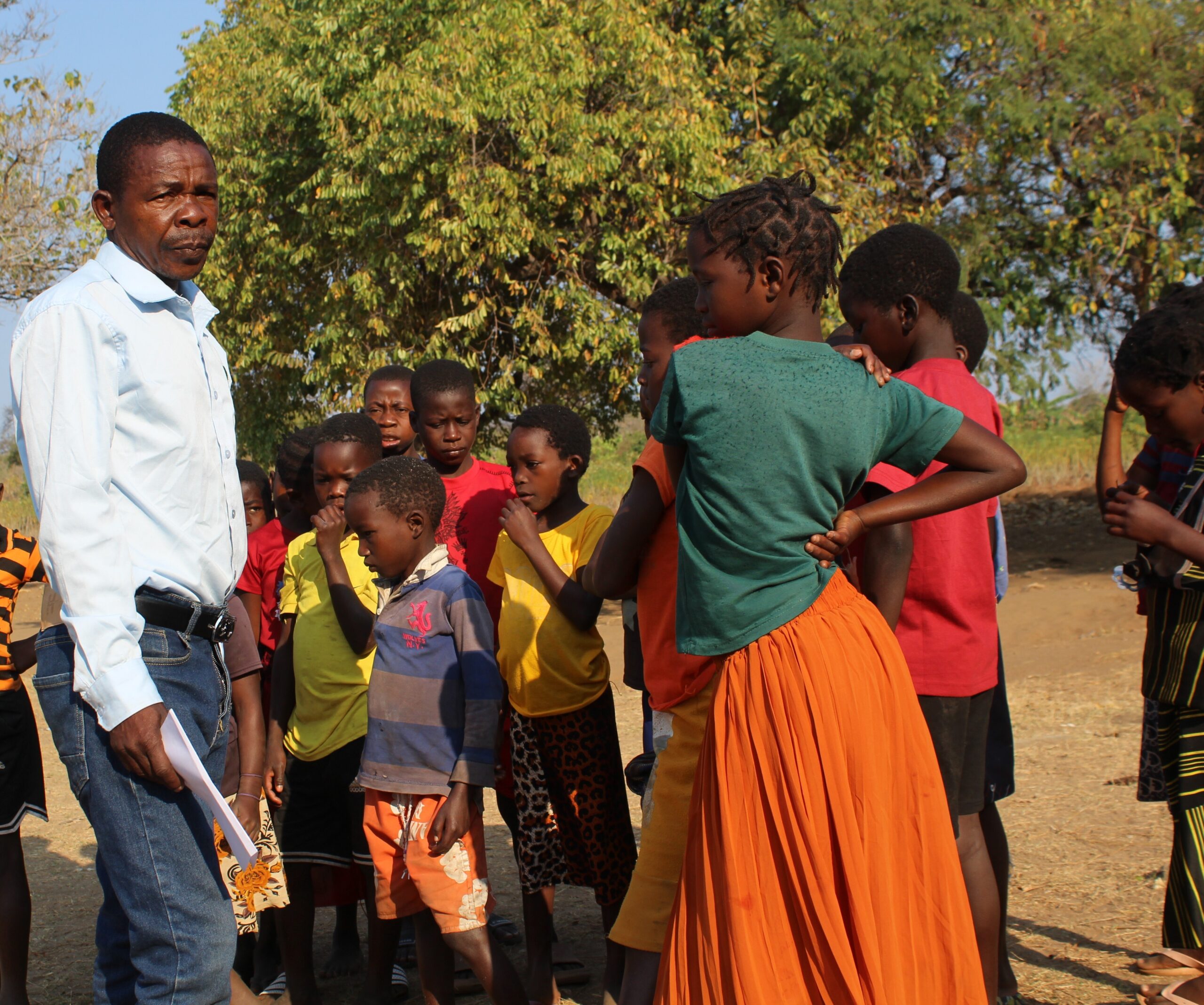 A teacher in Mozambique stands outside with his students.