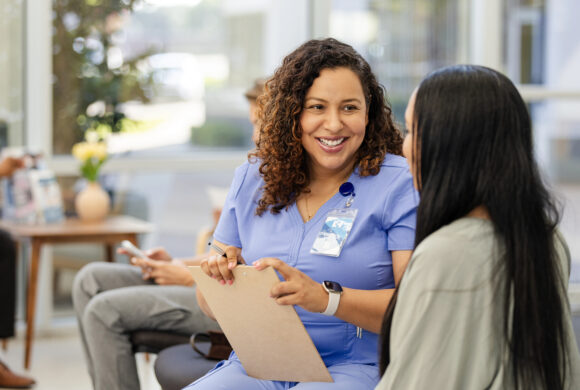 A female health worker speaks to a female patient in a clinic setting.