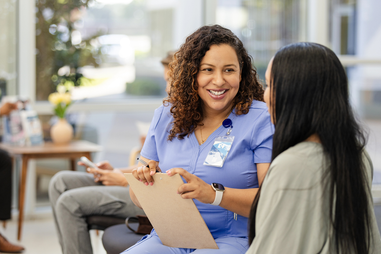 A female health worker speaks to a female patient in a clinic setting.